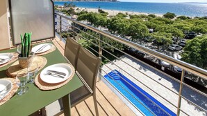 A balcony with a dining setup overlooking a beach and a pool. - Mileni I by Interhome (Roses)