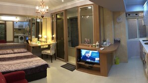 A hotel room with a bed, a desk with a chair, a television, and a kitchenette. - Dongqu Light Inn (Taipei)