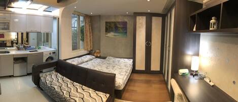 A compact bedroom with a bed, a small desk, and a window.