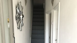 Un couloir avec des carreaux de sol à motifs, un escalier et un élément décoratif mural.