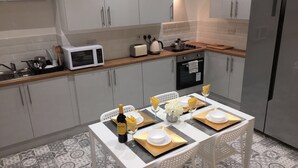 Une cuisine moderne avec des meubles blancs, un four à micro-ondes, une cuisinière et un réfrigérateur.