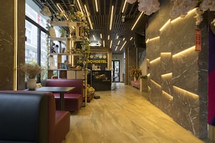 Interior moderno de un hostal con zonas de estar, una recepción y un letrero con el nombre del hostal.
