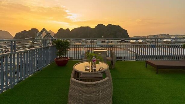 Une terrasse sur le toit offrant une vue sur les montagnes au coucher du soleil, avec des sièges d’extérieur et une rambarde.