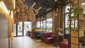 Un intérieur moderne avec des coins salon, des étagères en bois et de grandes fenêtres.