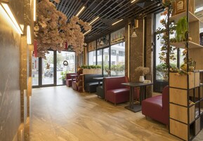Un interior moderno con zonas de estar, estanterías de madera y grandes ventanales.