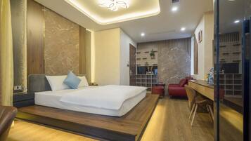 Una habitación de hotel moderna con una cama grande, un escritorio y una zona de estar.