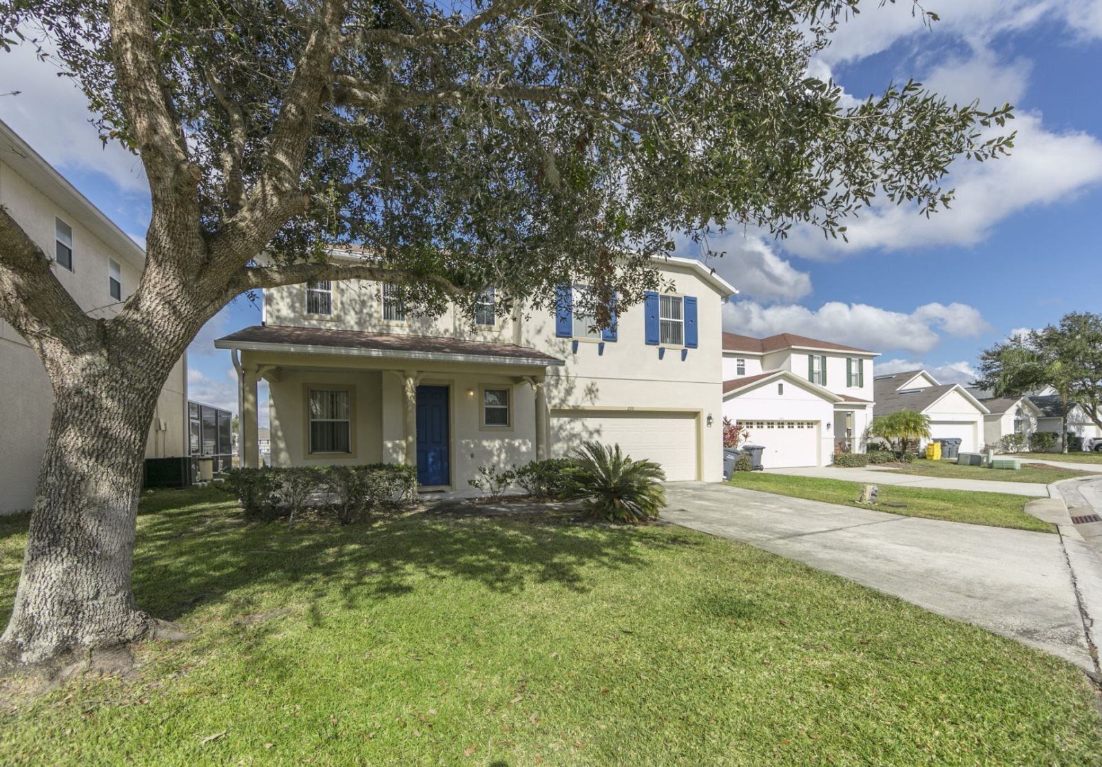 A two-story house with a front porch, a garage, and a well-maintained lawn.