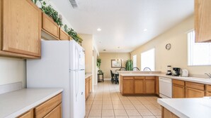 A modern kitchen with wooden cabinets, a white refrigerator, and a dining area with chairs and a table. - Bridgewater_at_town_center_233 (Davenport)