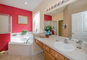 A modern bathroom with a white bathtub, a large mirror, and a sink. - Emerald_island_2761 (Kissimmee)