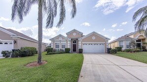 A residential building with a central garage, a well-maintained lawn, and a palm tree. - Windsor_palms_8144 (Kissimmee)