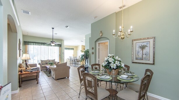 A dining area with a round table set for six, surrounded by wicker chairs. - Windsor_palms_8144 (Kissimmee)