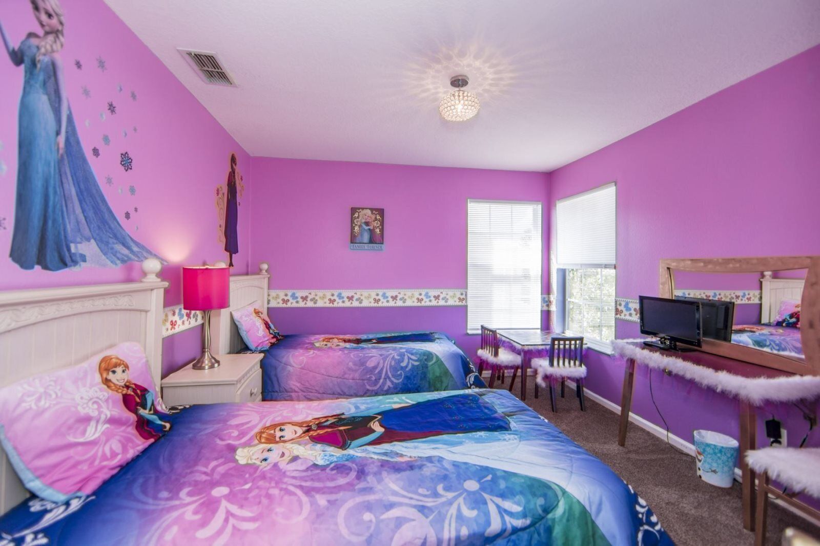 A bedroom with two beds, a desk, a chair, a television, and a window.