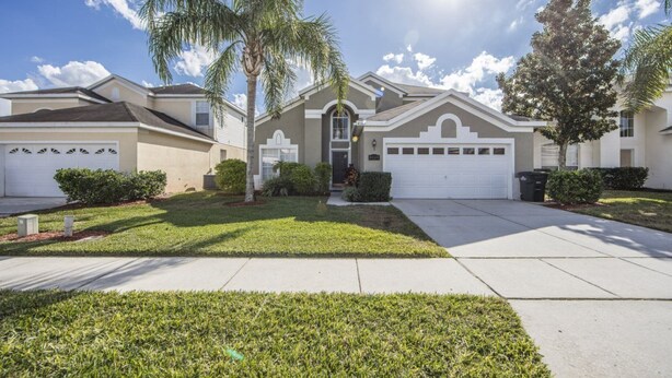 A residential house with a front yard, two garages, and a palm tree. - Windsor_palms_8169n (Kissimmee)