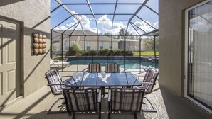 A covered patio with a glass enclosure, a pool, and outdoor furniture. - Windsor_palms_8169n (Kissimmee)