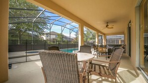 A covered patio area with a pool, outdoor furniture, and a ceiling fan. - Emerald_island_8520 (Kissimmee)