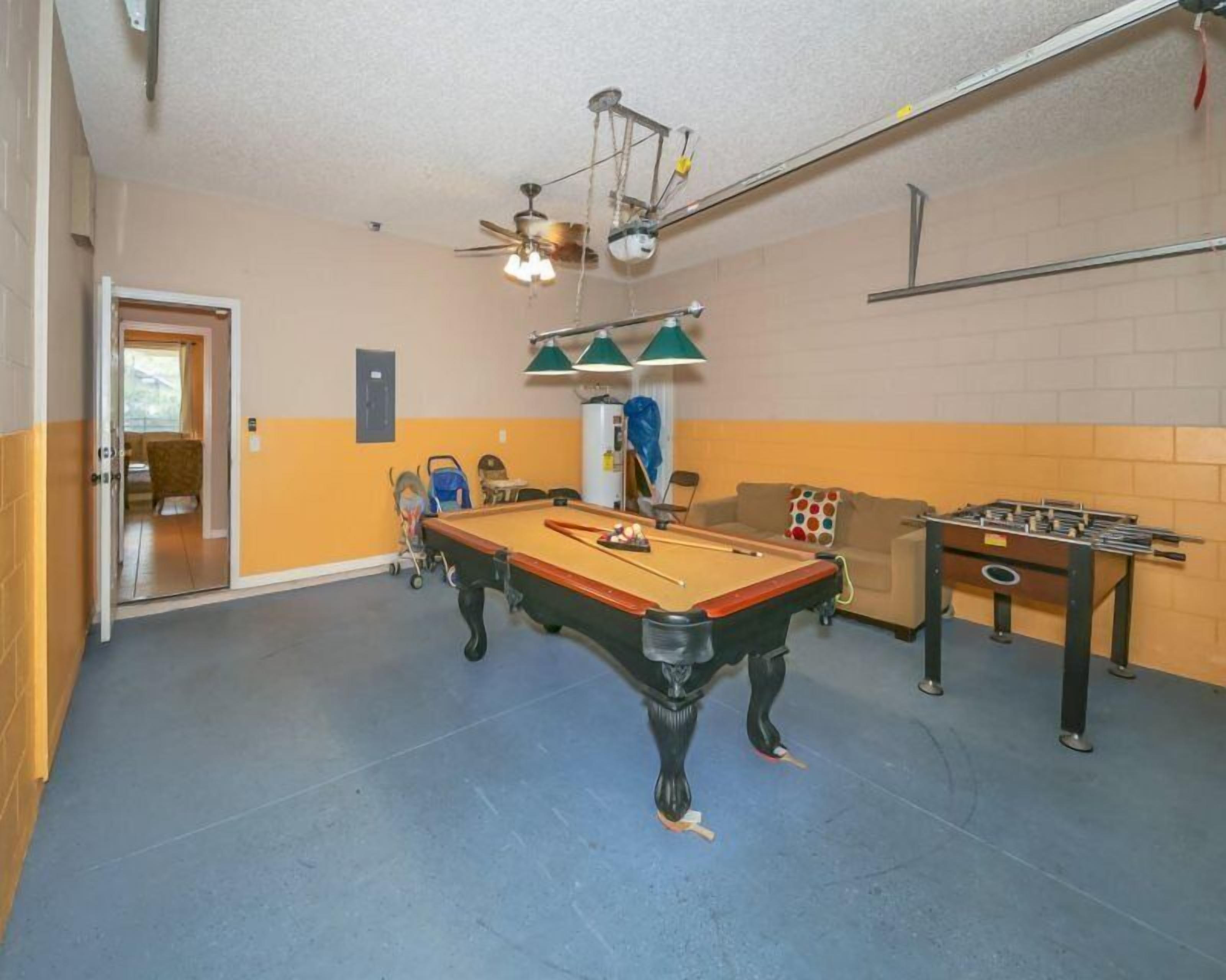 A recreational room with a pool table, a foosball table, and a ceiling fan.