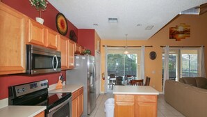 A modern kitchen with wooden cabinets, stainless steel appliances, and a central island. - Emerald_island_8520 (Kissimmee)