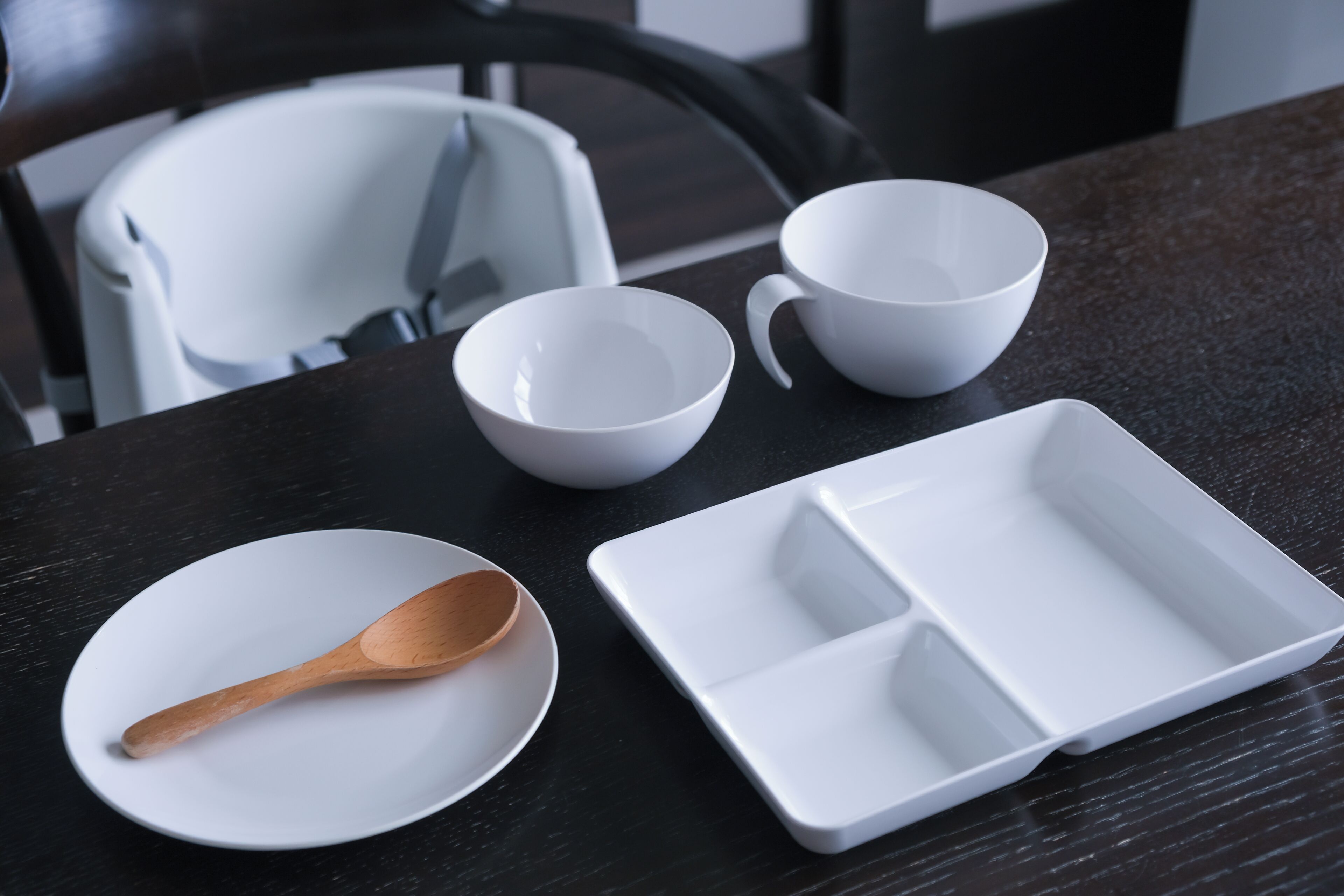 Une table à manger avec de la vaisselle blanche et une cuillère en bois.