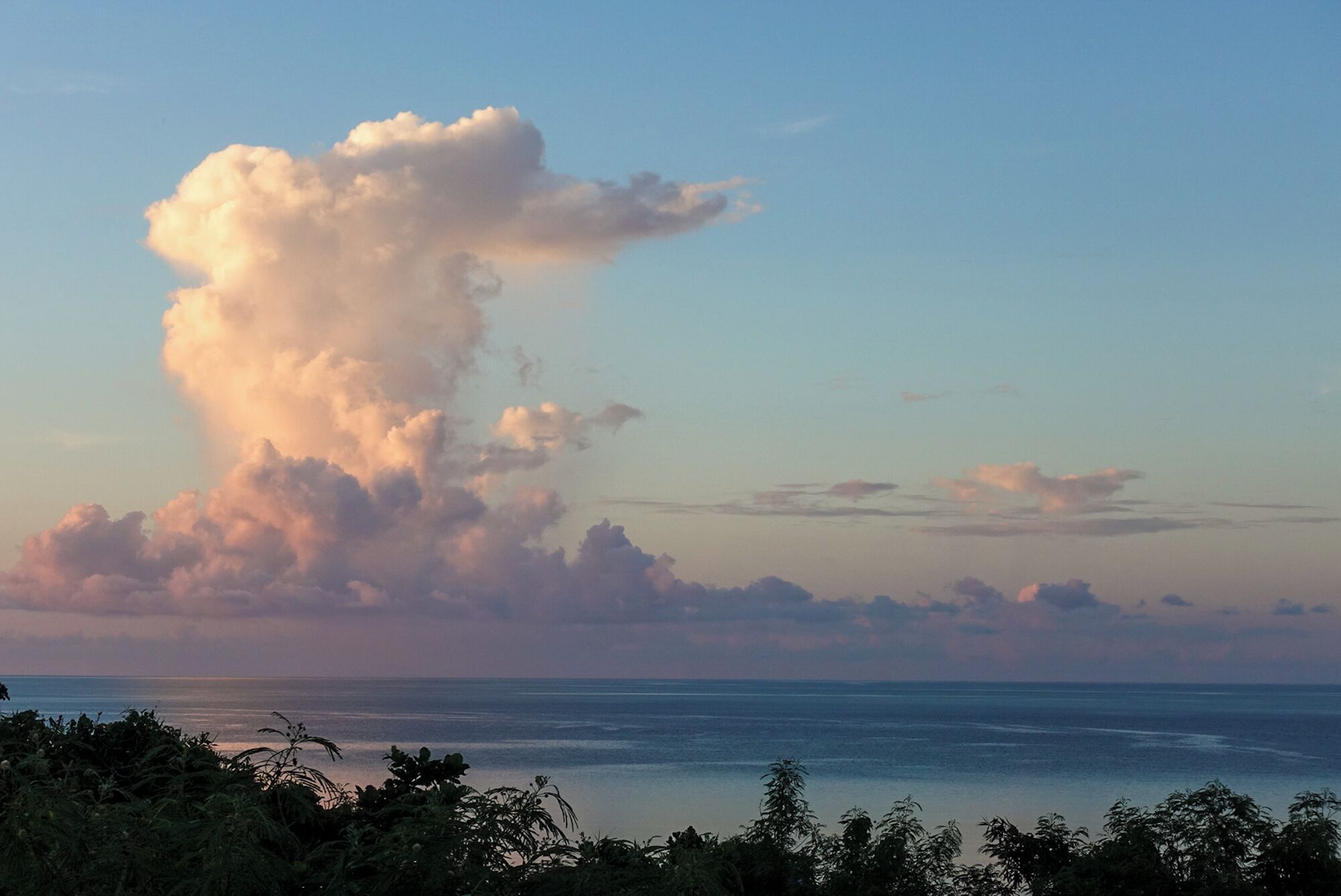 A coastal landscape with a large cloud formation and a view of the ocean.