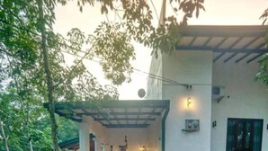 A covered outdoor area with a stone wall and a paved walkway leading to a building entrance. - Seethawaka Royal Resort (Hanwella)