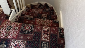 A staircase with a white railing and patterned carpet. - Lamplighter Guesthouse (Plymouth)