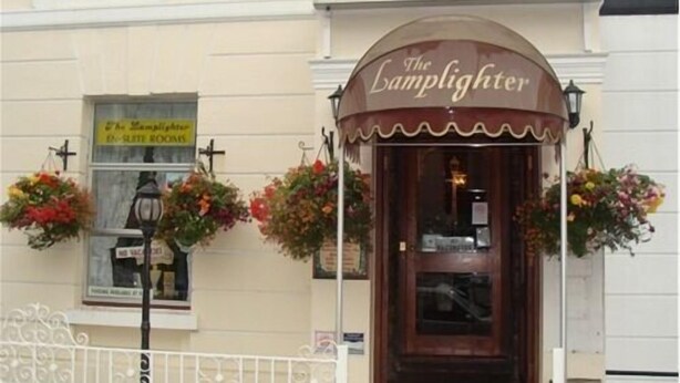 The Lamplighter, a building with a sign above the entrance and a window with a sign below. - Lamplighter Guesthouse (Plymouth)