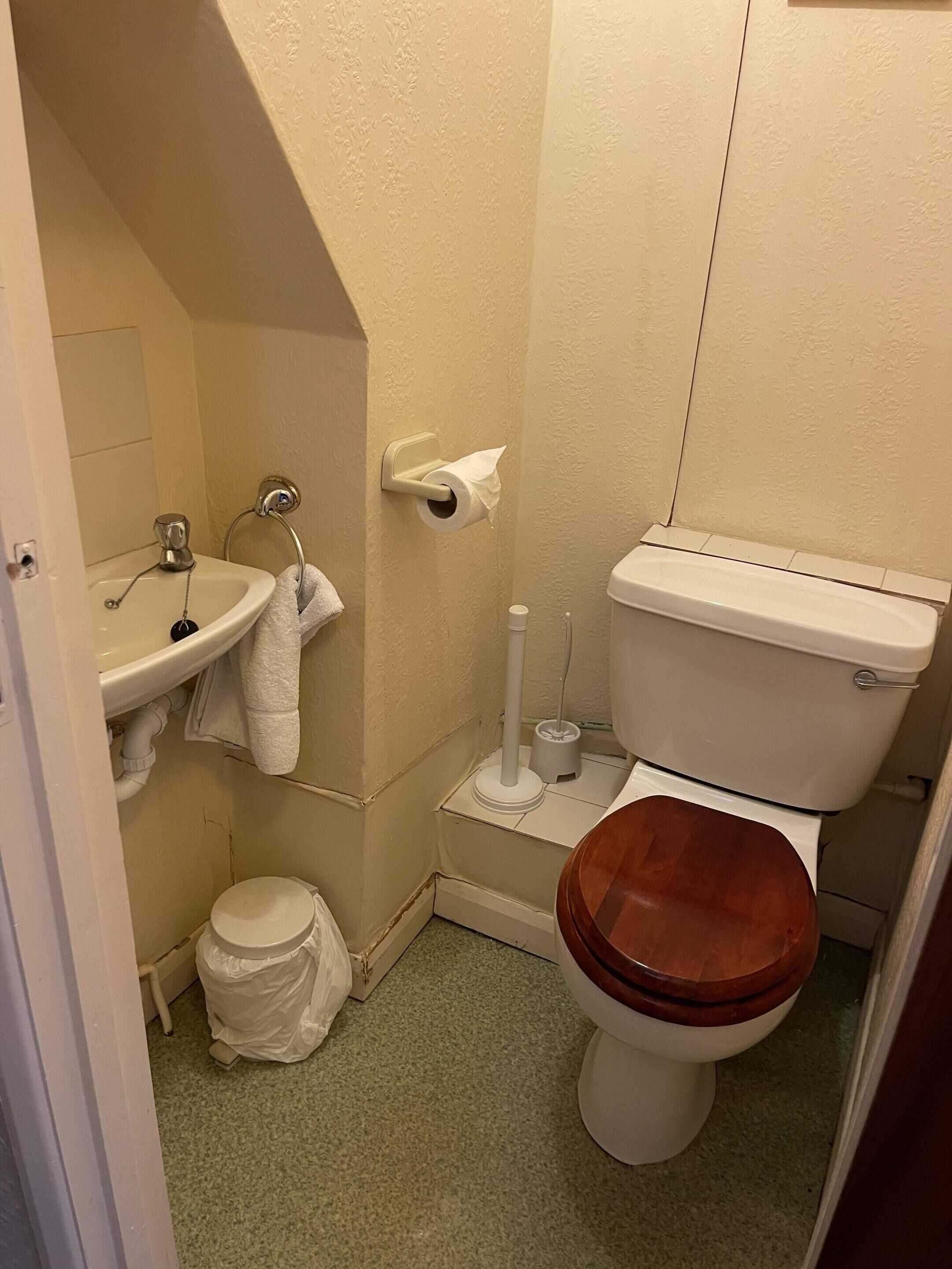 A small bathroom with a sink, toilet, and a shower area.