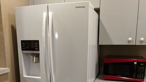Uma cozinha com geladeira Samsung, micro-ondas e armários cinzas.