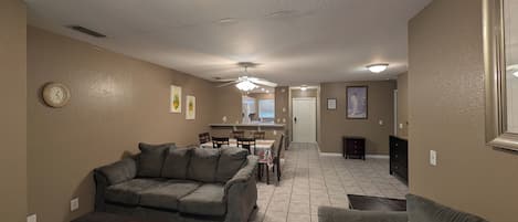 A living room with a sofa, a coffee table, and a dining area with chairs and a table.