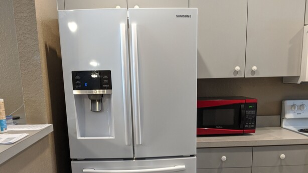 Cozinha com geladeira de aço inoxidável, micro-ondas vermelho e dispenser de água branco.