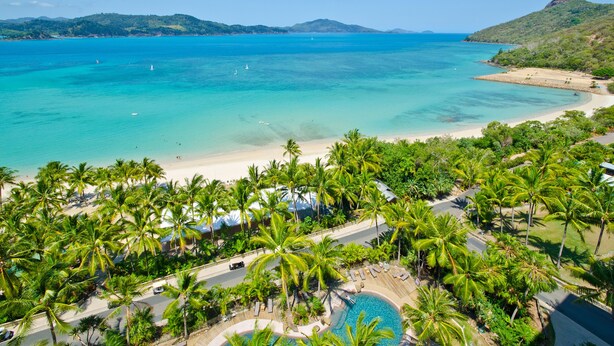 A tropical resort with a pool, palm trees, and a beach. - Whitsunday Apartment on Level 6 (Whitsundays)