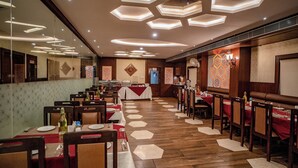 Un restaurant avec des luminaires hexagonaux au plafond, un plancher en bois et des nappes rouges.