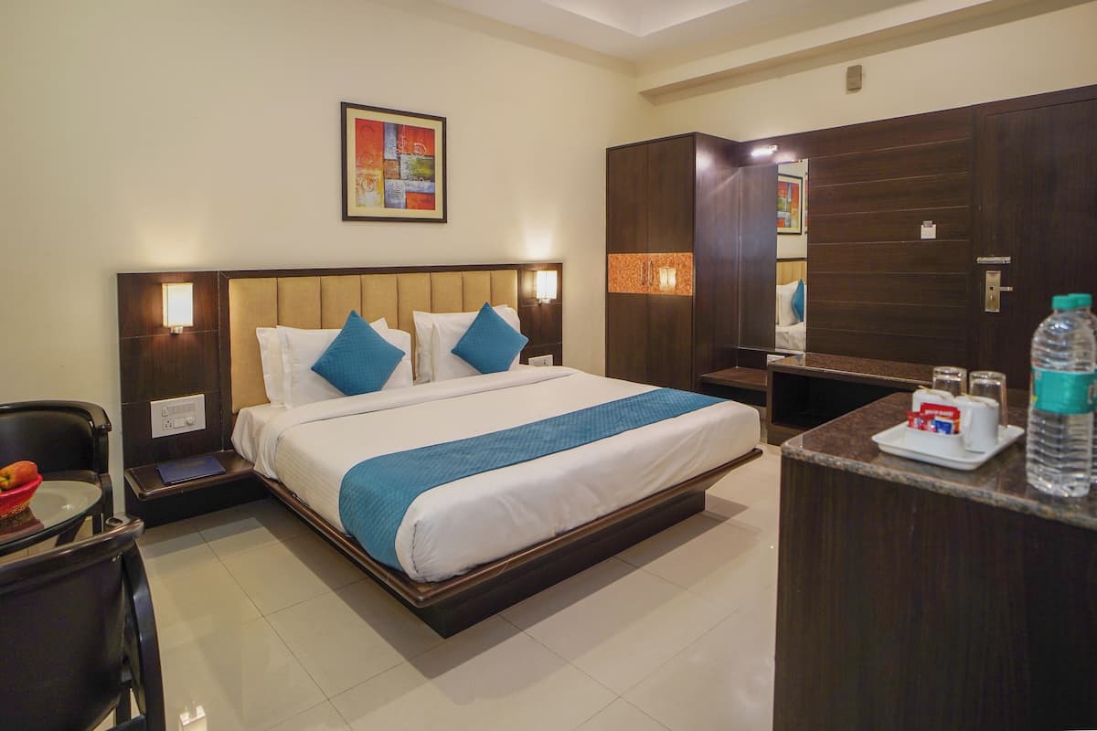 A hotel room with a large bed, bedside tables, a desk with a chair, and a wardrobe.