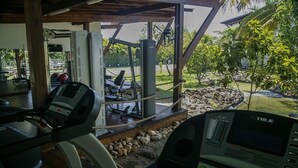 Ein Fitnessraum mit Cardiogeräten und Blick auf einen Garten.