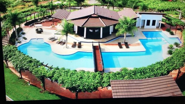 Ein Resort mit großem Schwimmbad, mehreren Gebäuden und üppiger Bepflanzung.