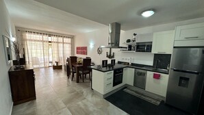 Eine moderne Küche mit weißen Schränken, einem Edelstahlkühlschrank und einem Essbereich mit Tisch und Stühlen.