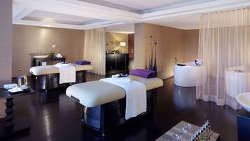 Relax in this serene spa room featuring two massage tables, a spacious bathtub, and a convenient sink area.
