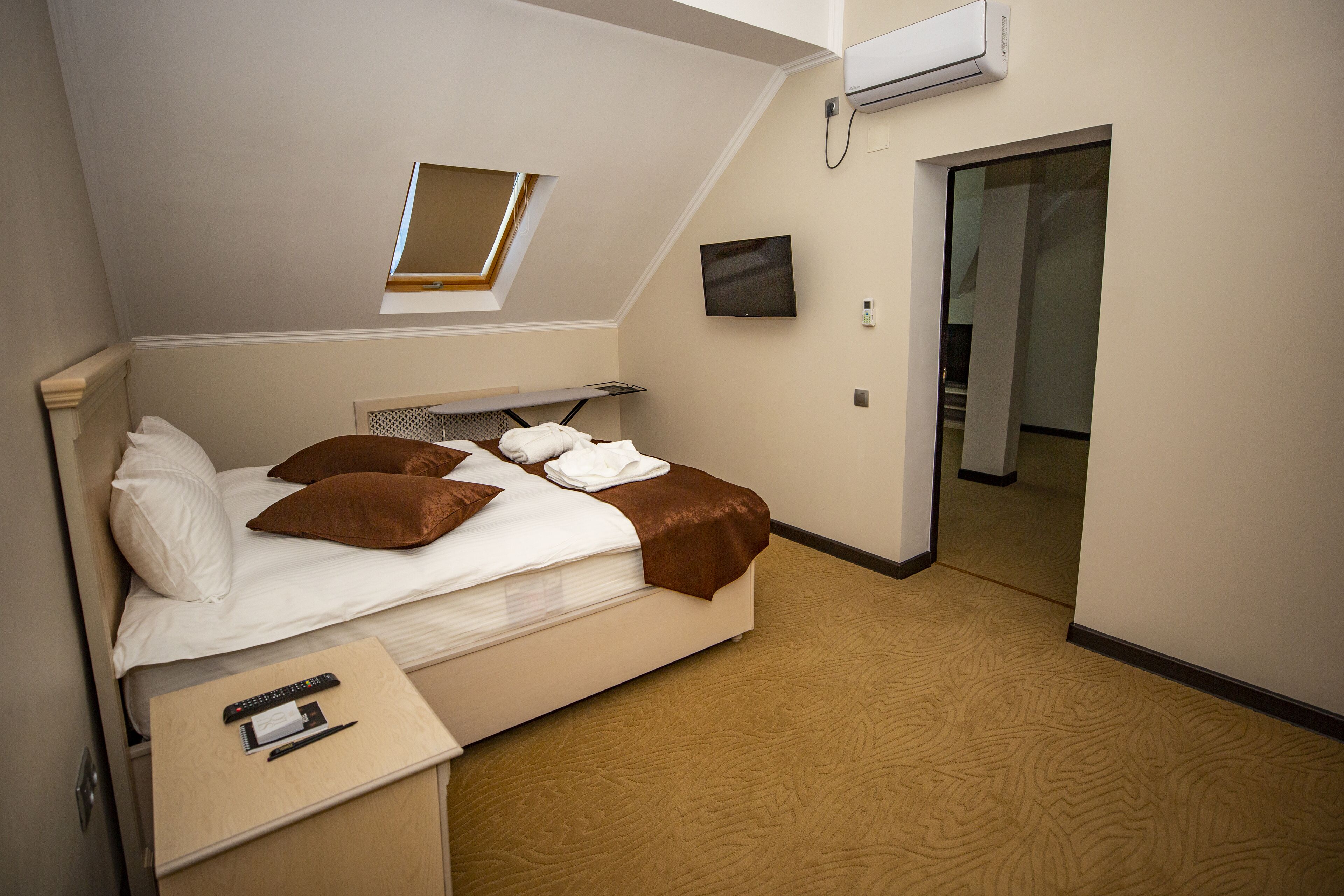 Una habitación de hotel con una cama, un escritorio, un televisor y una ventana.