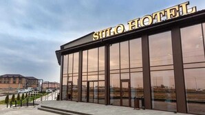 Een hotel met een moderne gevel, grote glasramen en een opvallend bord.