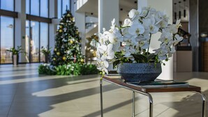 Een moderne ruimte binnenshuis met een groot raam, een kerstboom en een tafel met een bloemstuk.