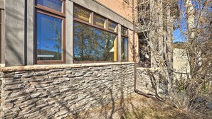 Un edificio con paredes de piedra y ventanas amplias que reflejan árboles.