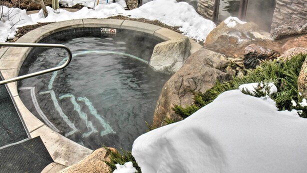 Un jacuzzi rodeado de nieve y rocas.