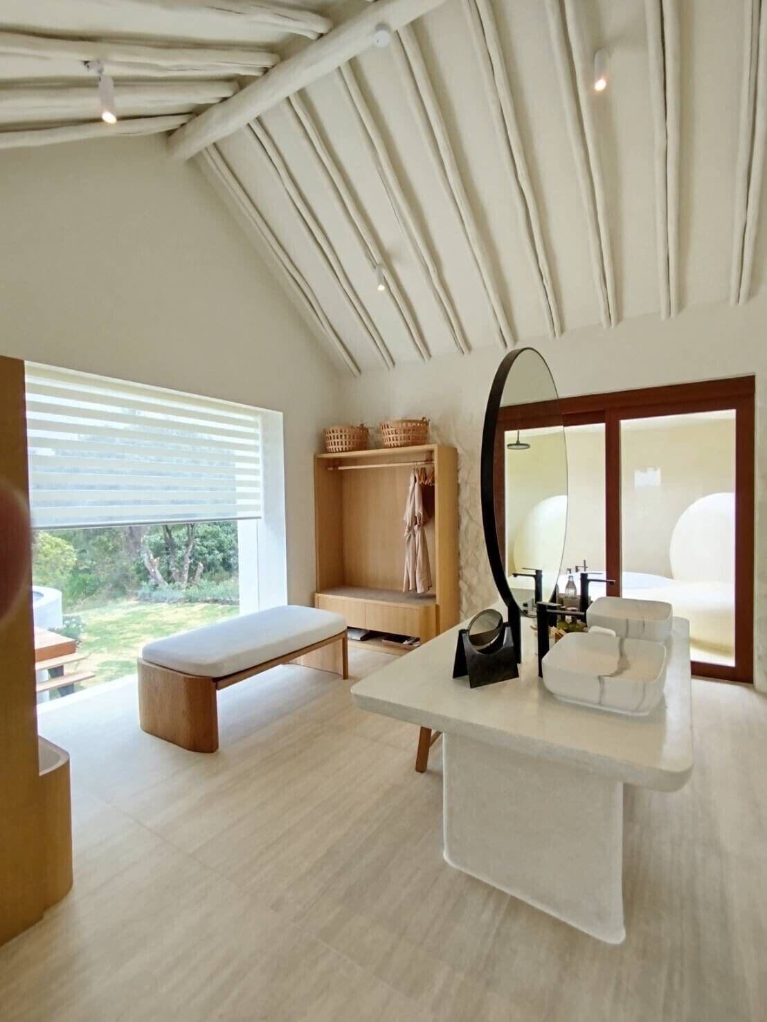 A modern bathroom with a large mirror, a bench, and a wooden vanity.