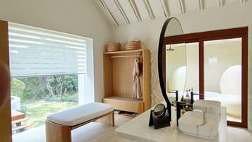 A modern bathroom with a large mirror, a bench, and a wooden vanity.