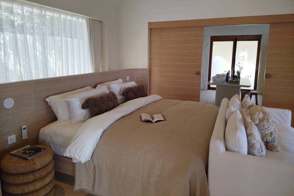 Un dormitorio con una cama grande, una mesita de noche, un espejo y una ventana con cortinas.