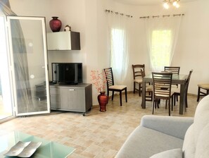 A living room with a sofa, TV, and a dining area with chairs and a table. - 0687 Villa Benicadims Jazmin (Beniarbeig)