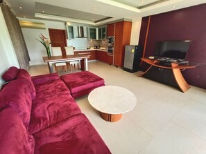 A modern living room with a red sectional sofa, a round coffee table, and a TV on a wooden stand.