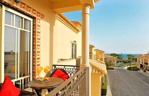 A balcony with a table, chairs, and a red cushion.