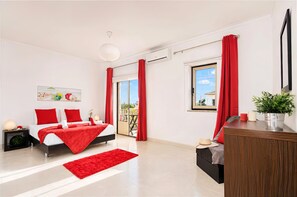 A modern bedroom with a bed, red curtains, a balcony, and a desk with a plant. - Comfortable apartment with pool in Albufeira (Albufeira)