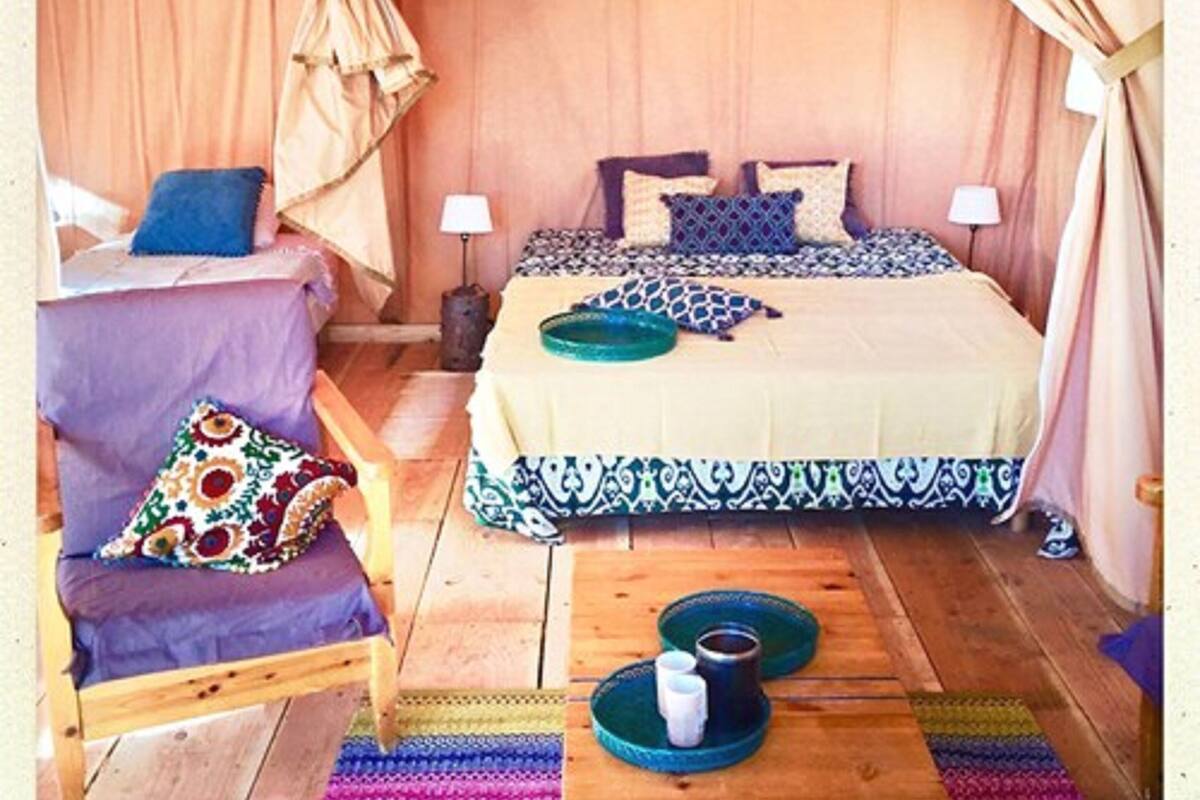 Un dormitorio acogedor con una cama, una silla, una mesita de noche y una pequeña mesa con tazas.